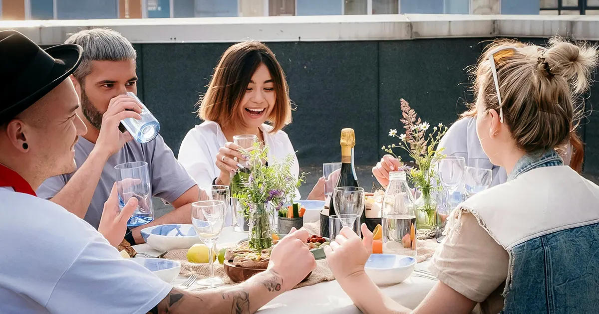 A group of friends sit outside having dinner at a picnic table during the warm Texas summer.