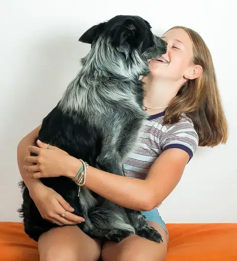 A young girl holding her dog.