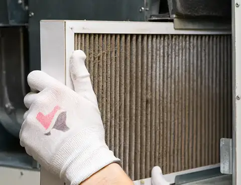 A CAST Heating & Air technician pulls a dirty filter from a customer's unit.
