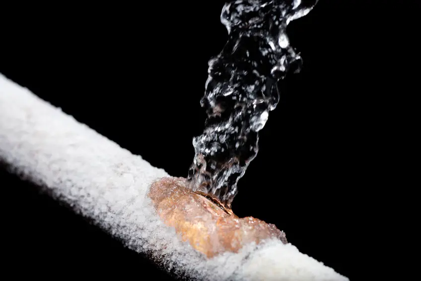 A frozen pipe bursts, and water sprays from within.