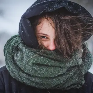 A young woman braves the harsh Texas winter in a scarf and hoodie.