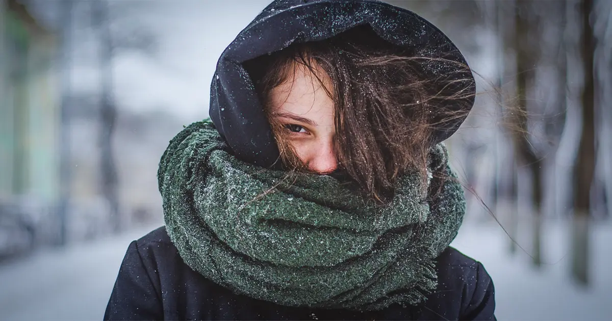 A young woman braves the harsh Texas winter in a scarf and hoodie.