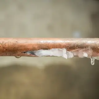 A copper pipe that has frozen solid and burst in the middle.